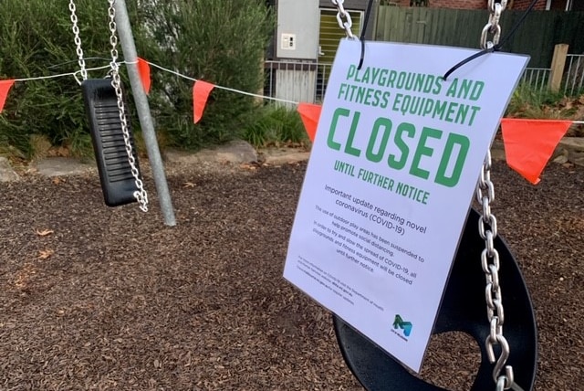 A laminated sign on attached to playground equipment saying the playground is closed.