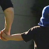 A generic image of a little boy holding his mother's hand while he wears a blue cap.