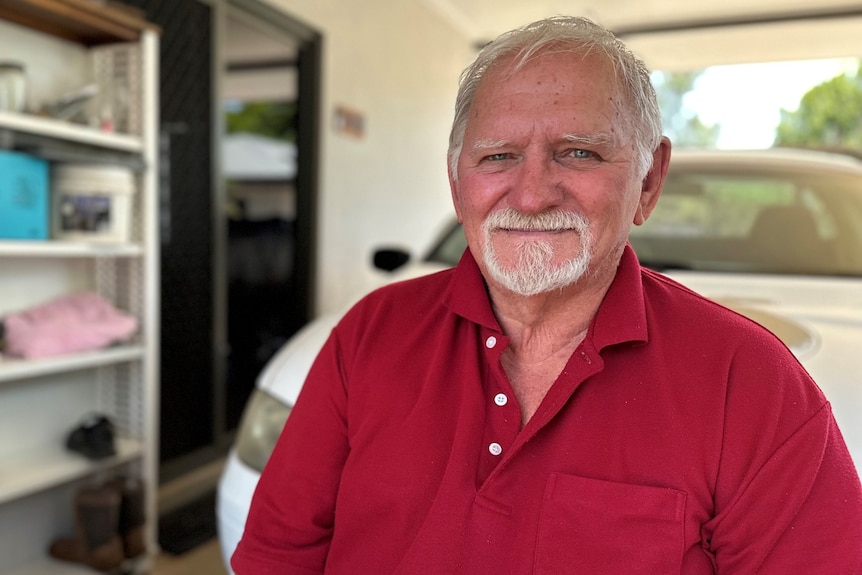 Photo of older man with white hair and beard wearing red shirt in his carport