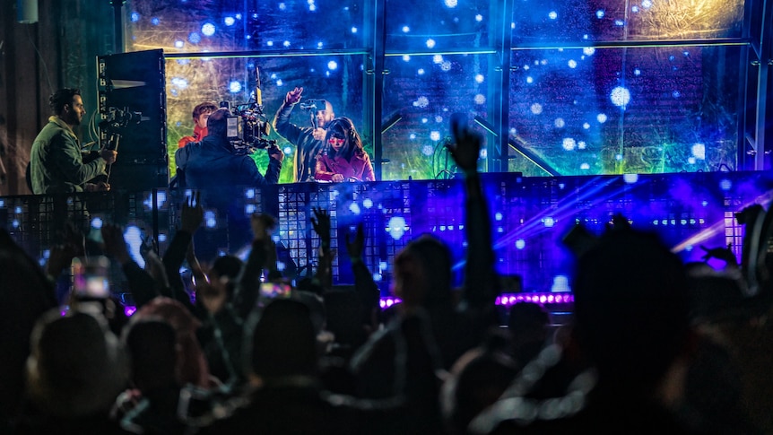 A DJ on a stage as a crowd dances in front of her 