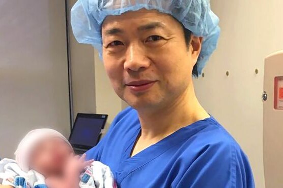 Dr John Zhang holding a baby.