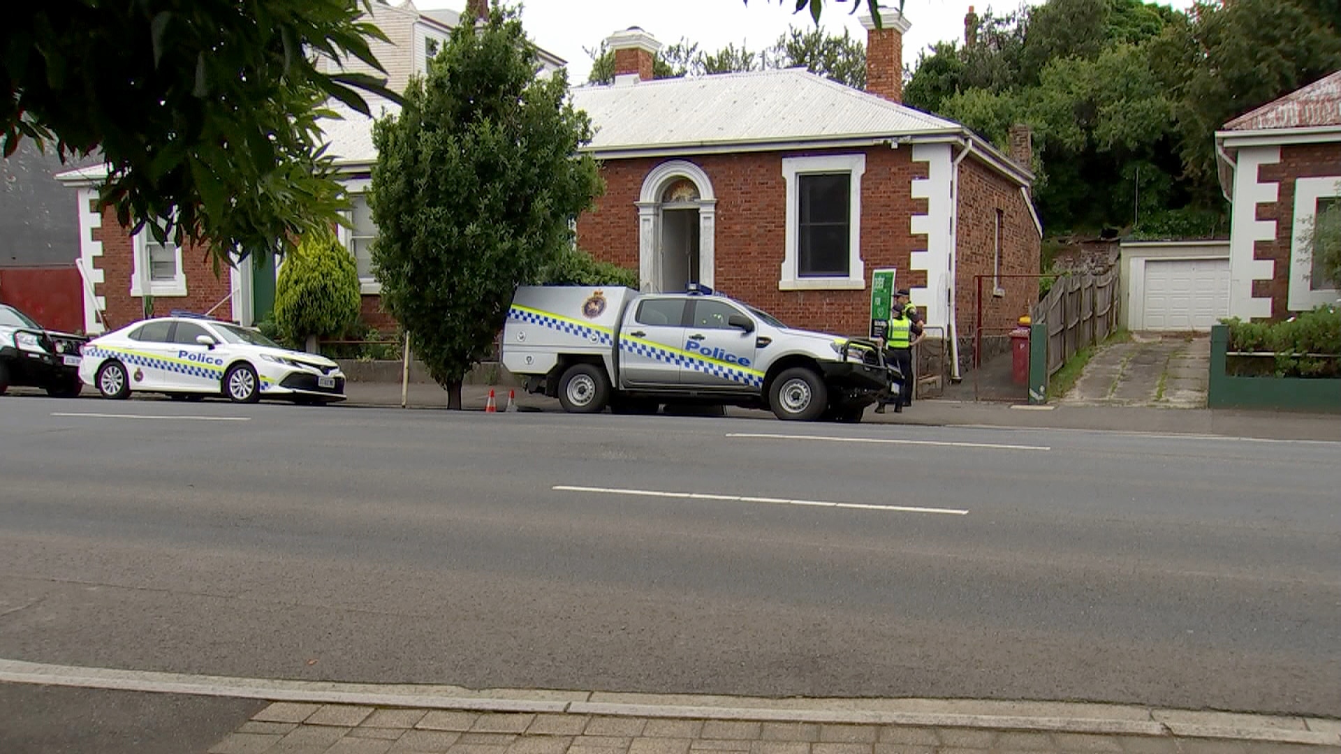 警车和警员停在一栋砖房外。