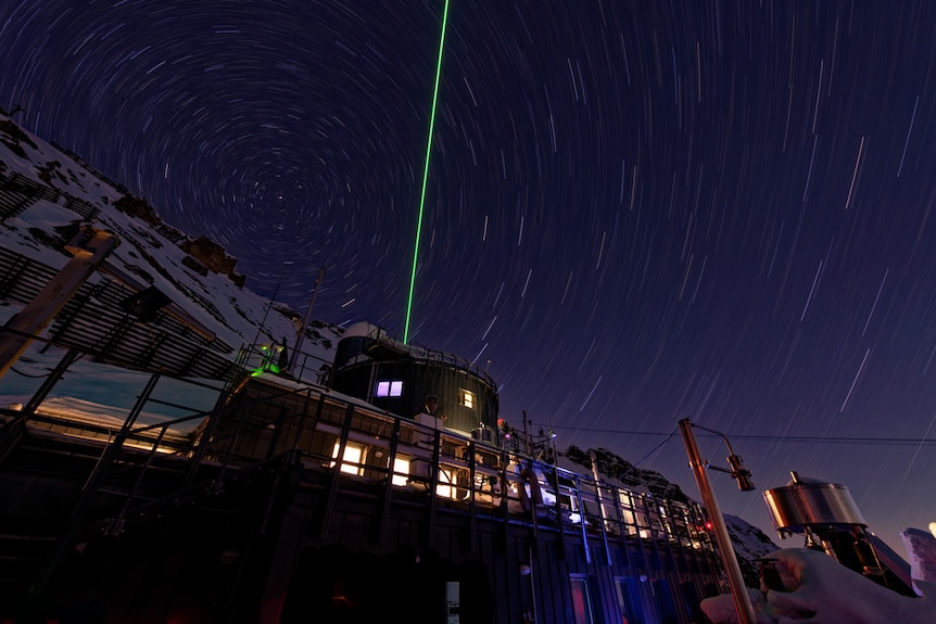 A green laser is fired into a swirling night sky from Schneefernerhaus