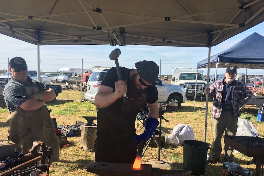 A blacksmith hammers a hot piece of metal.