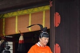 Japan's Crown Prince Akishino (in orange robe) attends a ritual ceremony.
