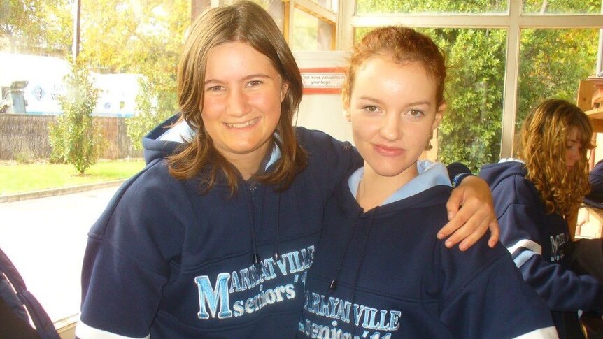 Two teenaged girls stand arm in arm with "Marryatville Seniors" written on their school uniforms.