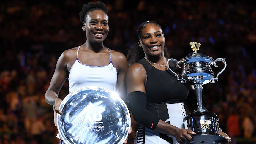 Serena (R) and Venus Williams show off their trophies after the Australian Open women's final.