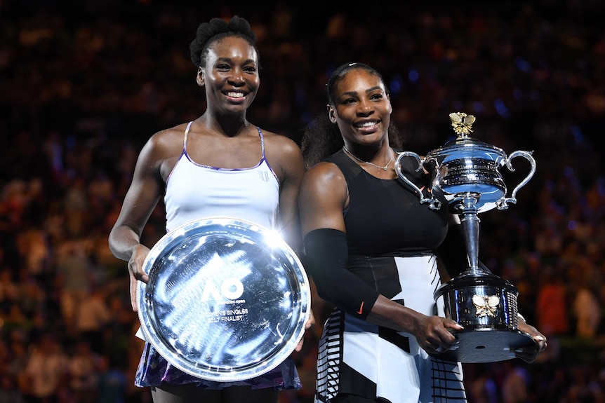 Serena (R) and Venus Williams show off their trophies after the Australian Open women's final.