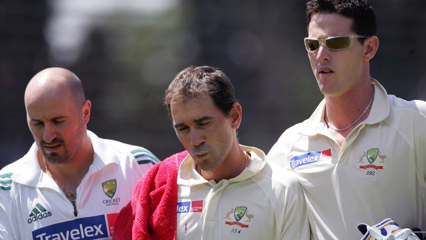 Justin Langer is helped off the cricket field by teammate Shaun Tait and physiotherapist Alex Conturi.