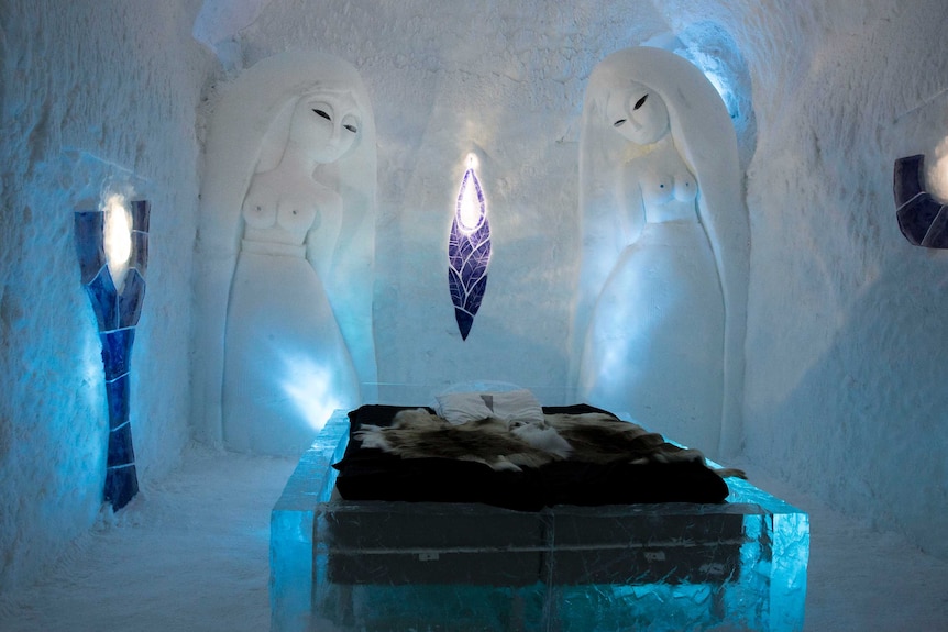 Two carved ice statues of angels in the wall look down on an ice bed.