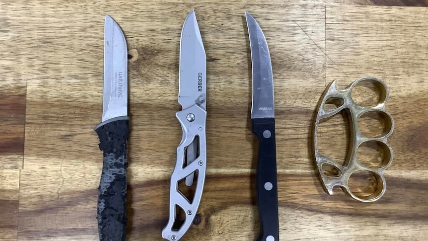 3 knives on a table alongside a knuckleduster