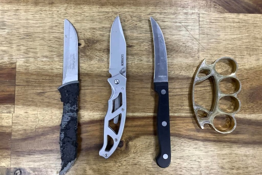 3 knives on a table alongside a knuckle duster