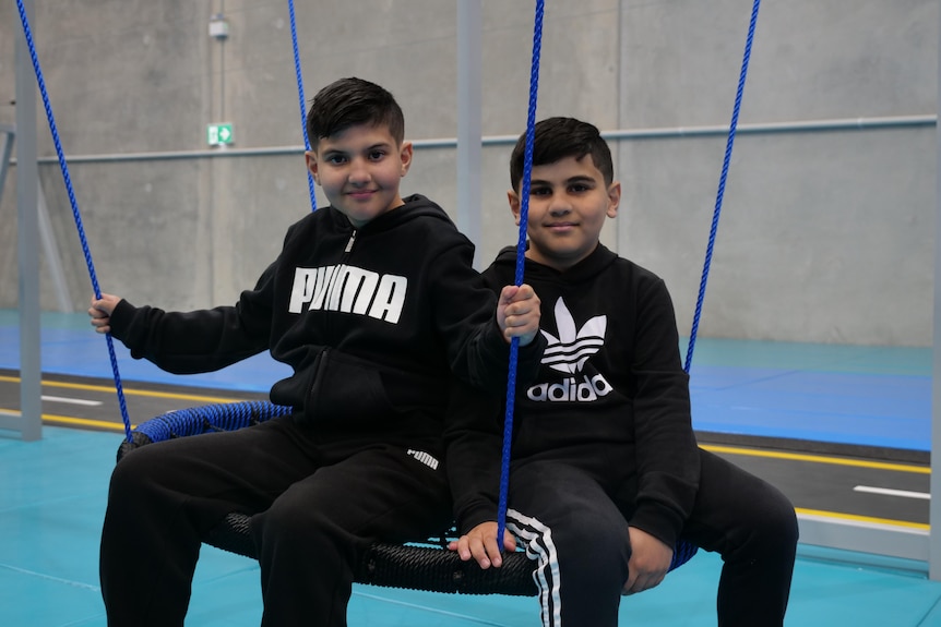 Two boys in black hoodies on a swing