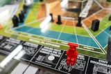 Close up of colourful boardgame mat with bright red piece front of frame.