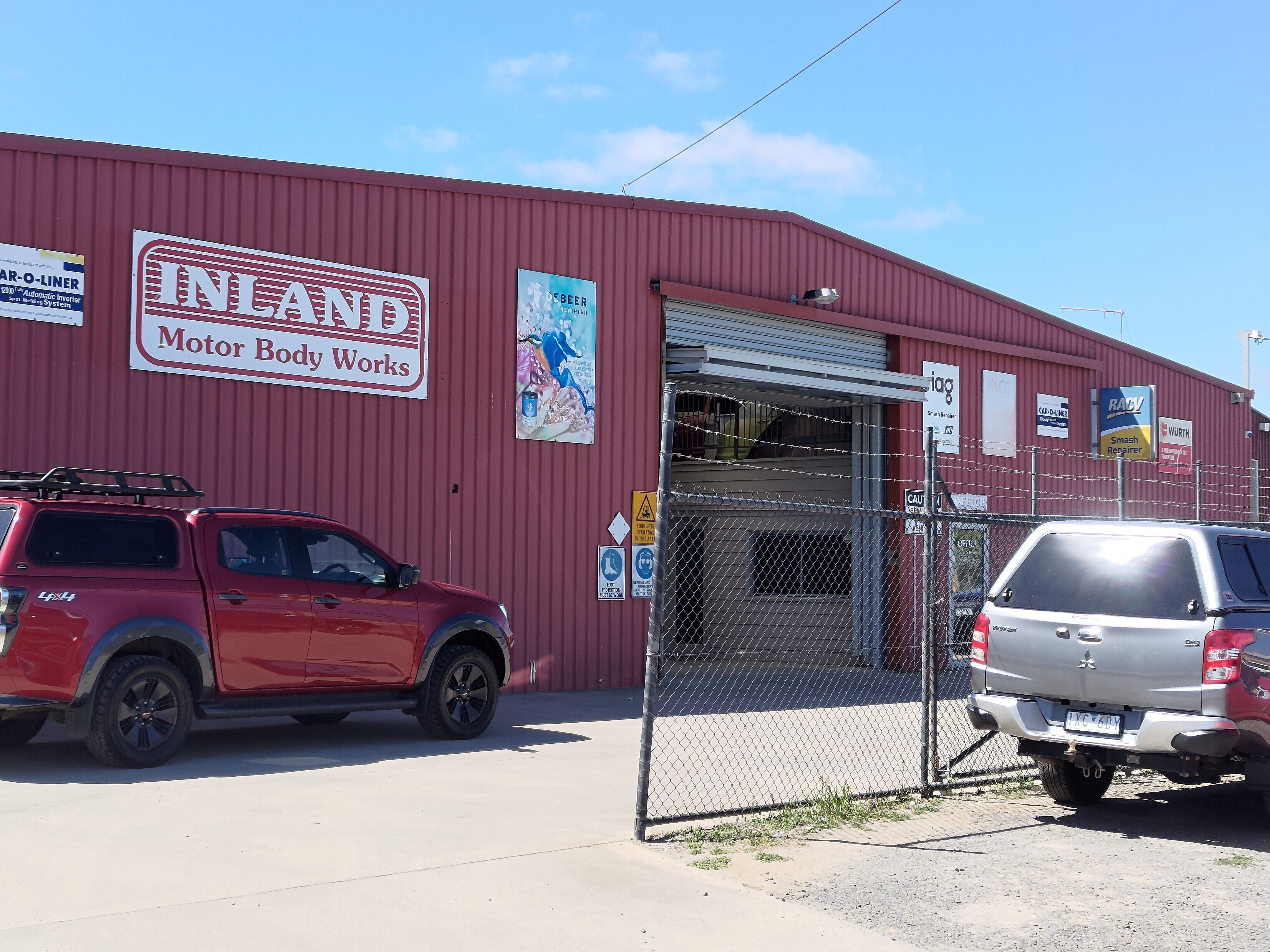 A red building with sign that says Inland Motor Body Works