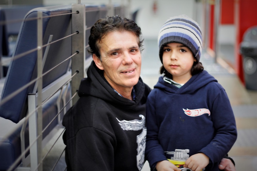 A man with a young boy, looking at the camera