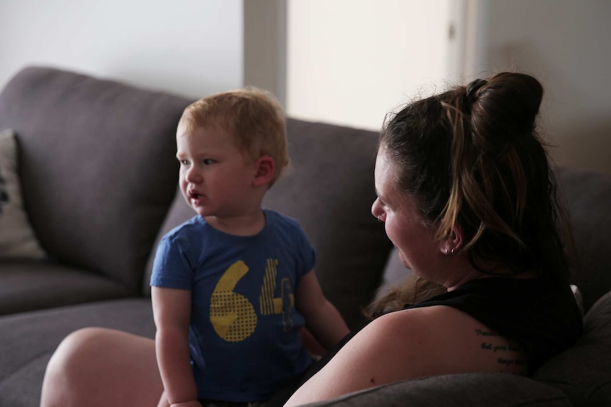 A woman sits with her children on a couch