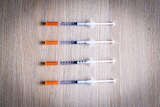 Four syringes of compounded semaglutide, lying on a table.