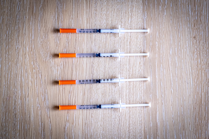 Four syringes of compounded semaglutide, lying on a table.