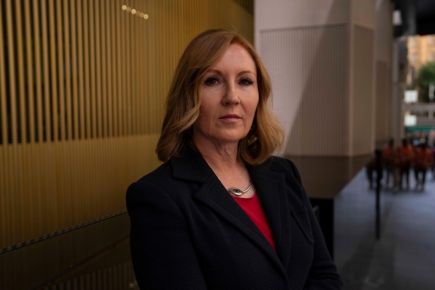 a woman in a suit looks into the camera