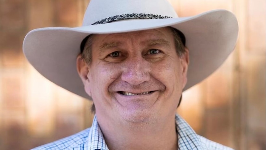 A man in a cowboy hat smiles at the camera