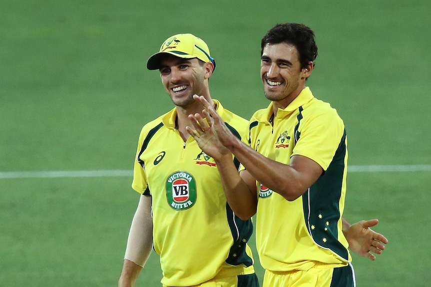 Two Australian cricket players celebrate together.
