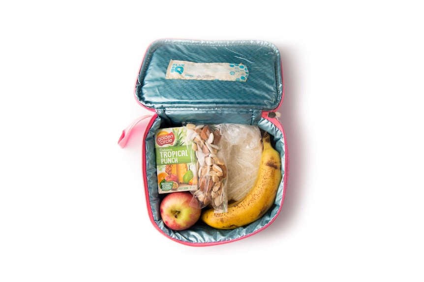 A peanut butter sandwich, nuts, a banana, an apple and a tropical fruit box in a pink cooler bag.