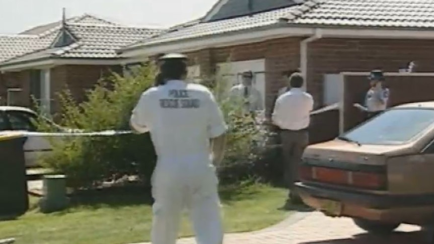 Police establish a crime scene around a blond brick suburban home.