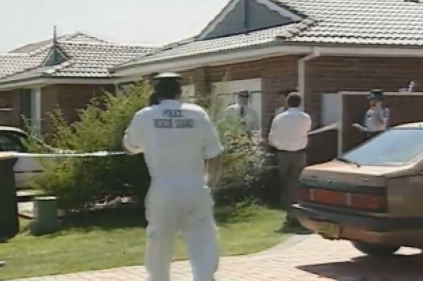 Police establish a crime scene around a blond brick suburban home.