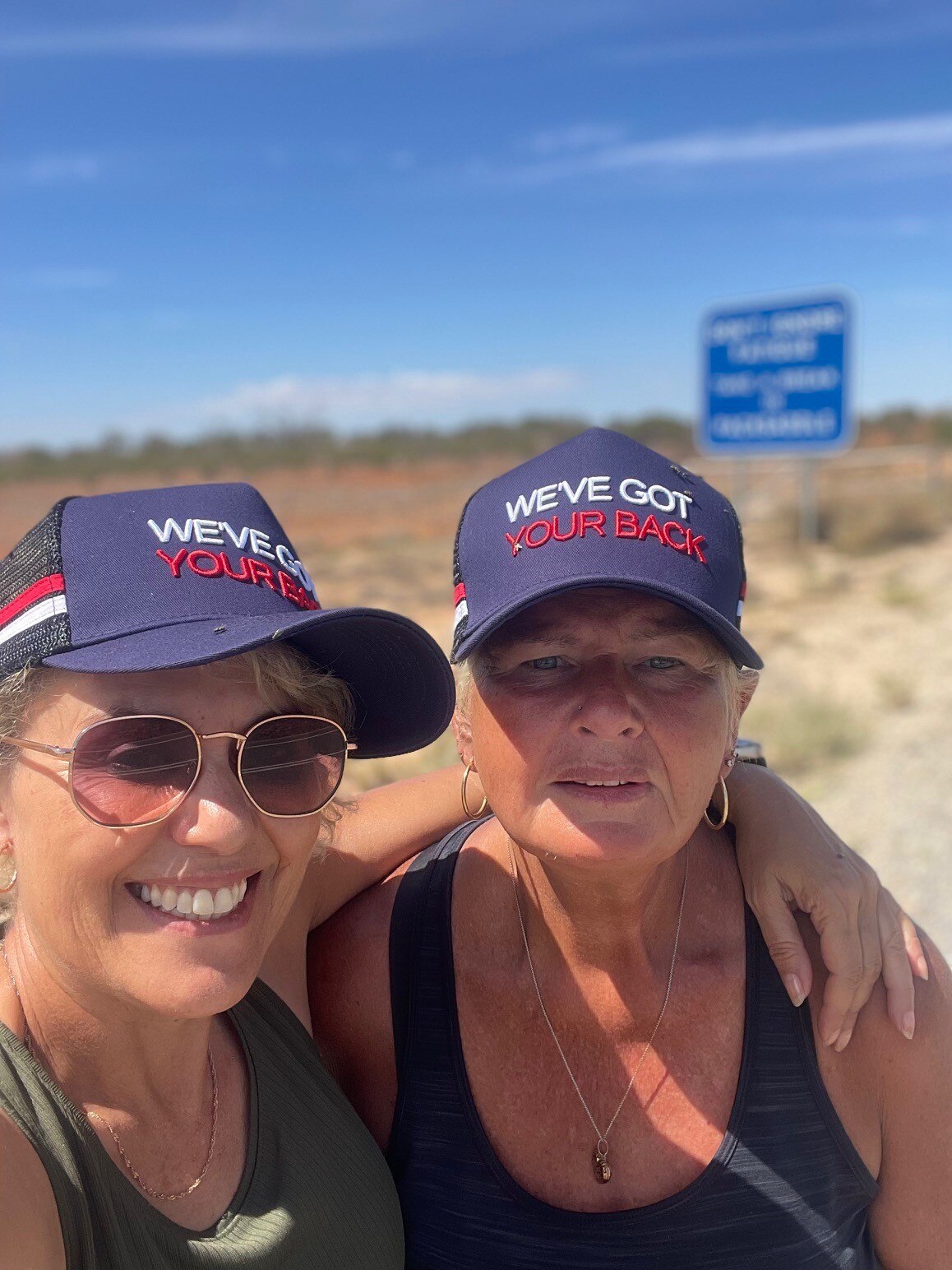 two women in a selfie, both wearing caps reading "we've got your back'.