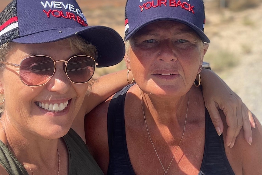 two women in a selfie, both wearing caps reading "we've got your back'.