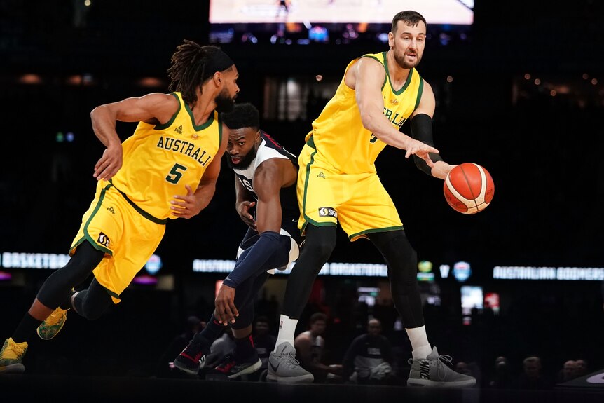 Andrew Bogut passes a basketball to a running Patty Mills during a game between Australia and USA.