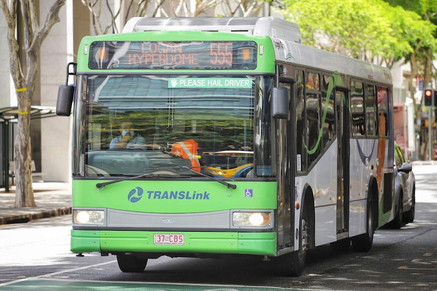 Bus driver wearing a mask in a green Logan City bus driving down Adelaide Street in Brisbane city on January 11, 2021.