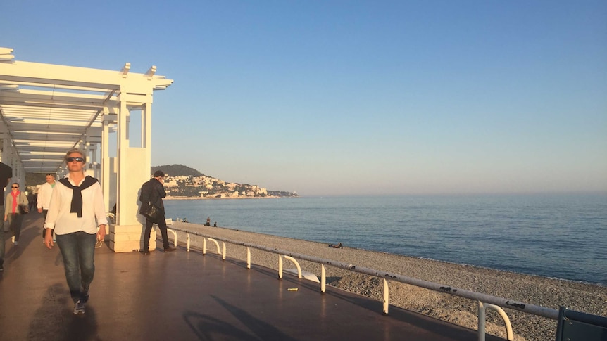 A woman strolls along the promenade in Nice, France