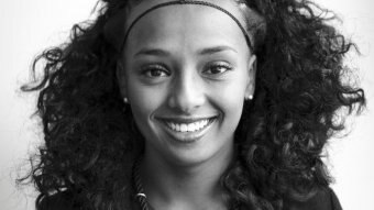 A black and white photo of a woman from Tigray with curly dark hair and a big smile.