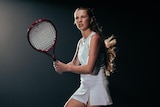 A female tennis player looks prepared to hit a ball