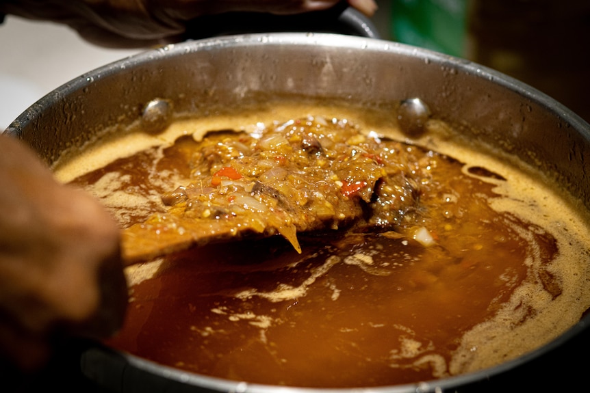 A spicy mix of chillies, onions, ginger, garlic and shrimp paste cook in a pot with oil.