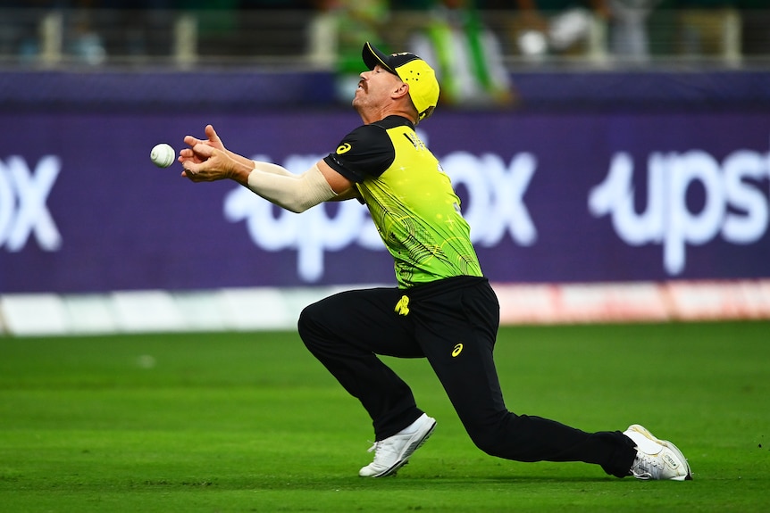 An Australian cricket players catches a cricket ball