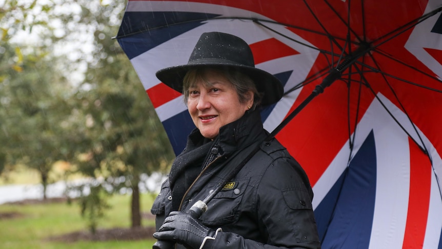 Vicki Treadell holding an umbrella and smiling past the camera