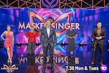 Hosts stand on the stage of the Masked Singer.