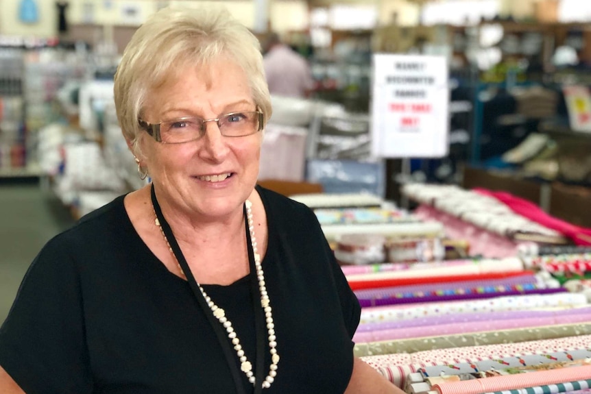 Woman with glasses standing in front of fabrics in a country department store.