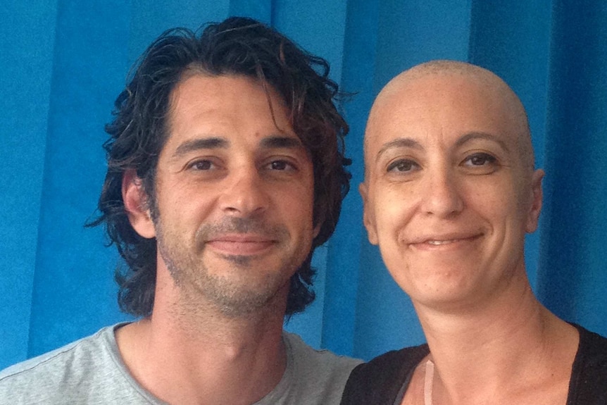 Andrea Zorbalas with a shaved head, posing with her husband during the stem cell treatment