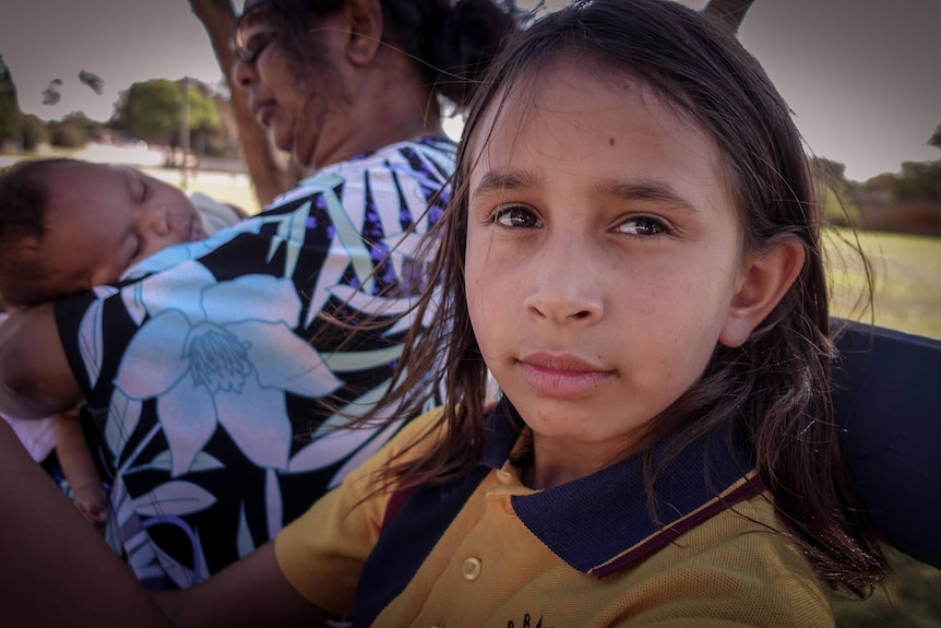 A young Aboriginal girl sits on a bench