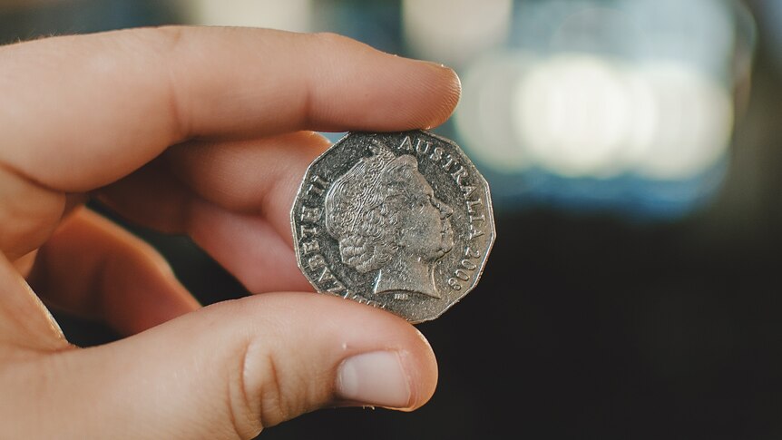 a 50 cent coin held up between and index finger and a thumb