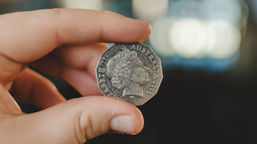 a 50 cent coin held up between and index finger and a thumb