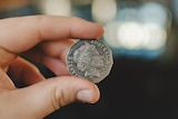 a 50 cent coin held up between and index finger and a thumb