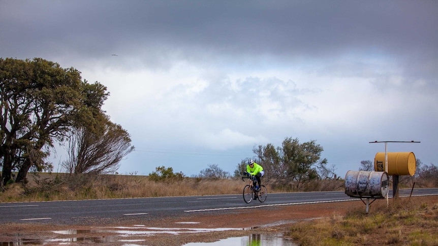 Mark Beaumont rides past two 44 gallon drum mailboxes in regional WA.