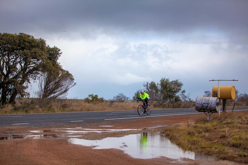 Mark Beaumont rides past two 44 gallon drum mailboxes in regional WA.