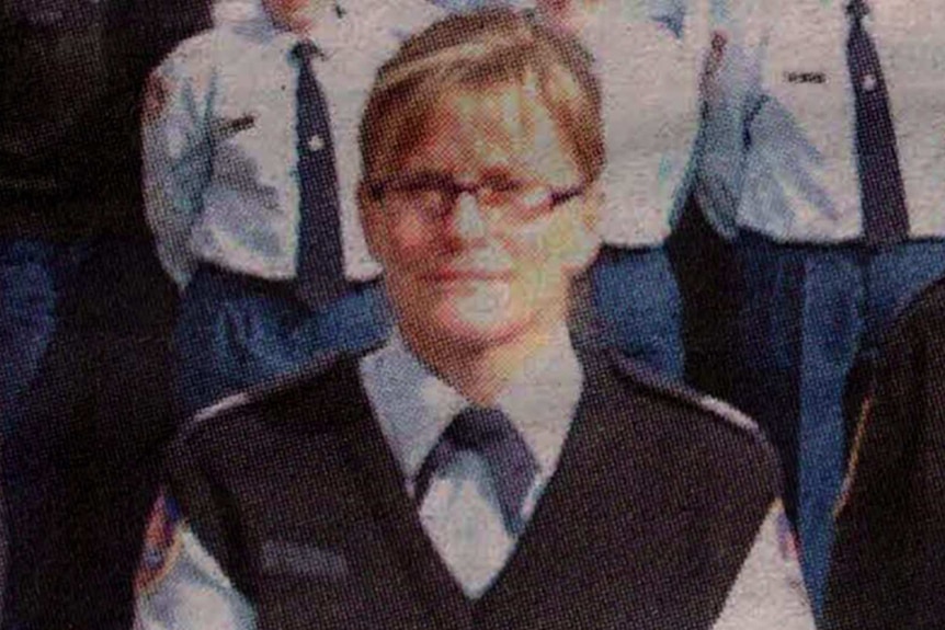 A woman in glasses standing in a formal photo in uniform.