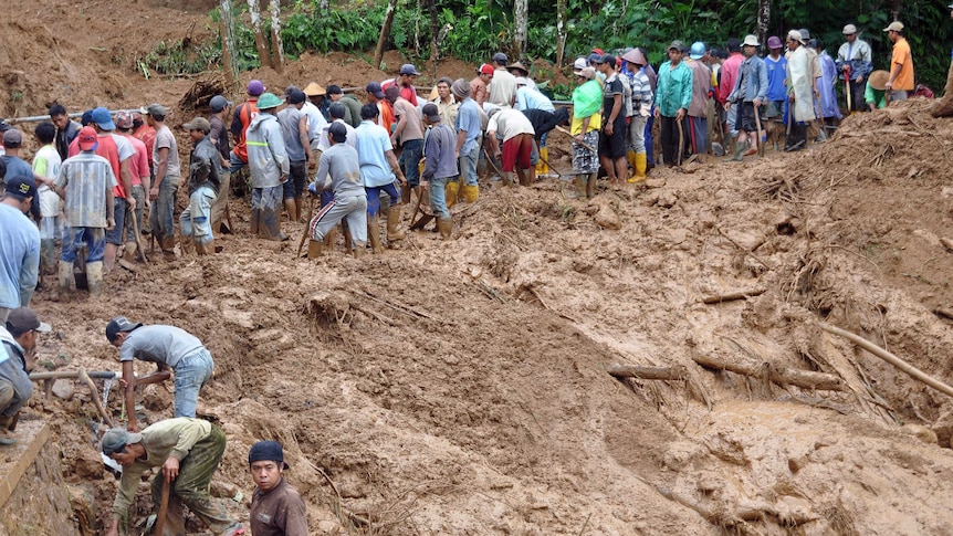 Indonesian villagers dig through mud
